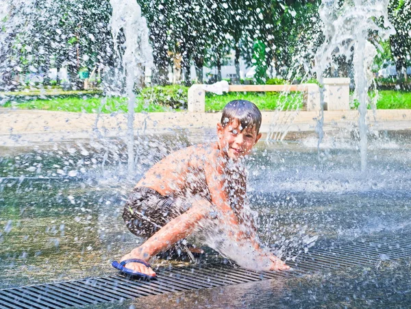 El chico está bañado en la fuente. — Foto de Stock
