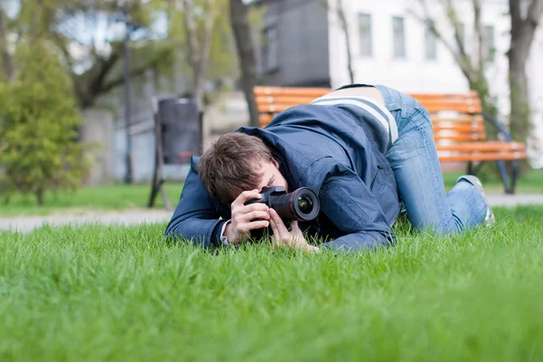 Fotós tart egy lövés a zöld fű — Stock Fotó