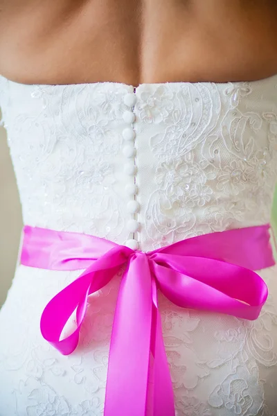 La schiena della sposa con un fiocco rosa sul vestito — Foto Stock