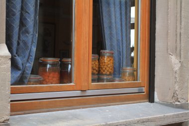 Window with blue curtaiins and jars of mirabell plums clipart