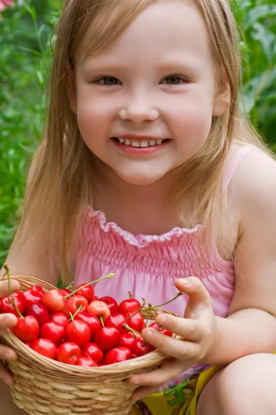 En vakker liten jente som holder en kurv med bær – stockfoto