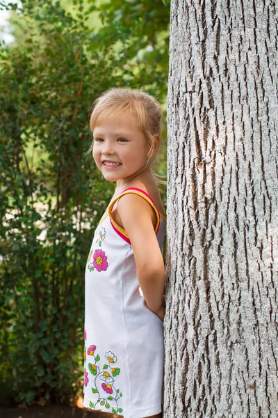 Menina bonita de pé ao lado de uma árvore — Fotografia de Stock