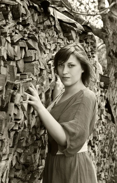 A young woman stands next to the logs — Stock Photo, Image