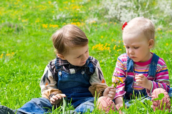 Menino e menina sentados na grama — Fotografia de Stock