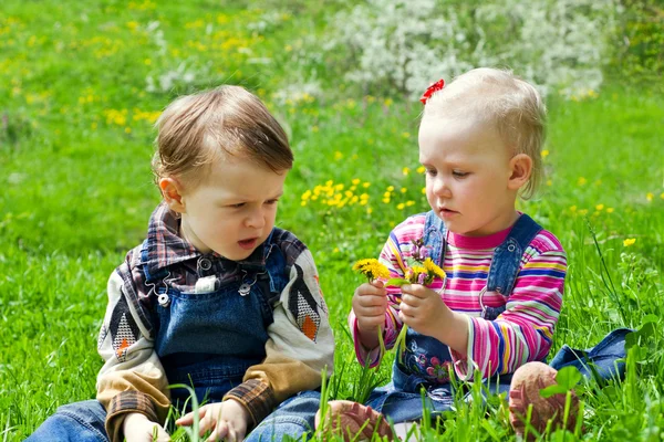 Jongen en meisje zit in het gras — Stockfoto