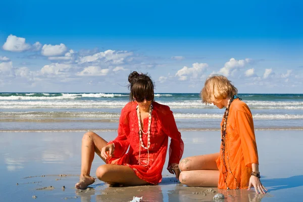 Två vackra kvinnor sitter på stranden — Stockfoto