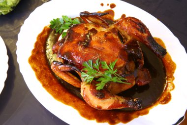 Roast chicken on a white plate with brown sauce clipart