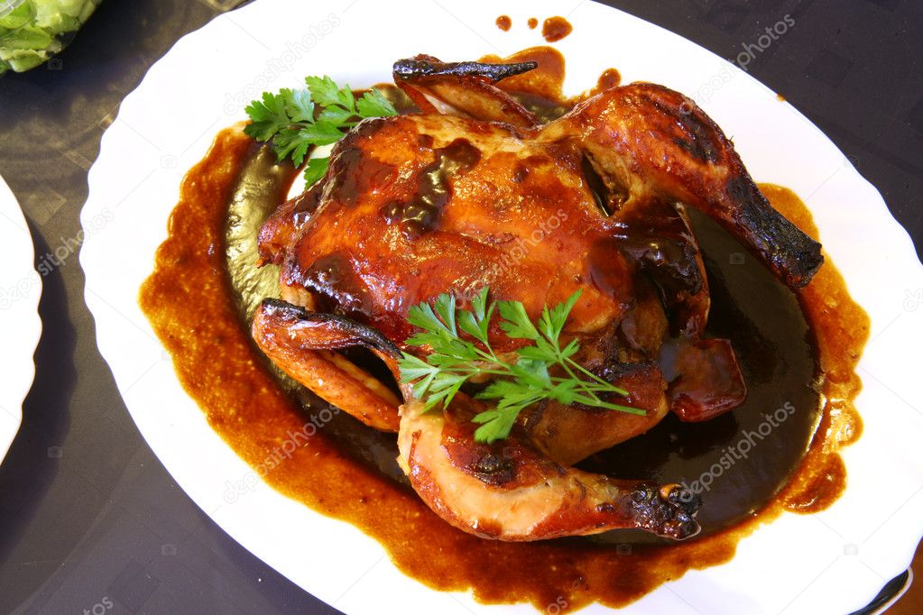 Roast chicken on a white plate with brown sauce