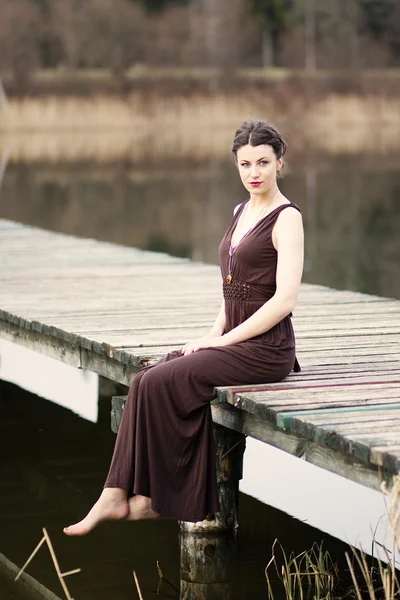 Yaya köprüsü üzerinde oturan genç güzel kadın — Stok fotoğraf