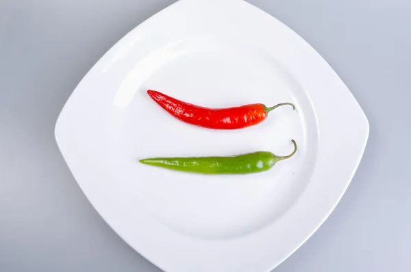 Red and green paprika on the plate — Stock Photo, Image