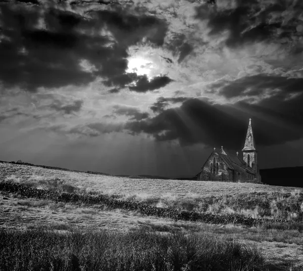 Dramatic and moody black and white image of a church on a hill being lit by — Stock Photo, Image