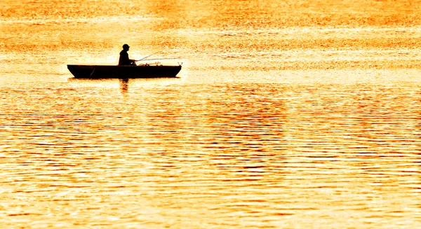 Um pescador de pesca de um punt no brilho da noite — Fotografia de Stock