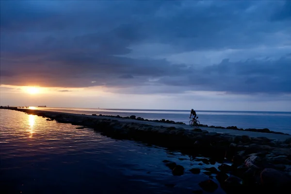Ciclista sul molo al tramonto — Foto Stock