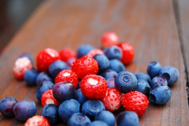 Colourful berries on wooden table clipart