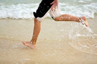 Young man jogging at the beach clipart