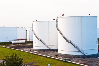 Tank çiftliğinde benzin ve petrol için mavi gökyüzü olan beyaz tanklar