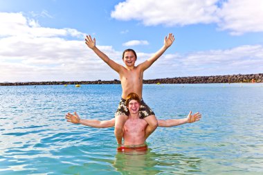 Brothers having fun together in the beautiful ocean clipart