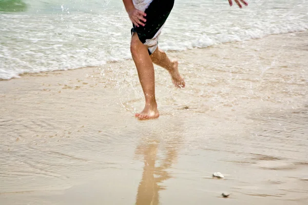 Молодой человек бегает по пляжу — стоковое фото