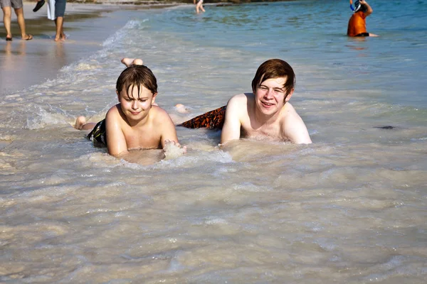 Hermanos están tumbados en la playa y disfrutando del sol y la wa —  Fotos de Stock