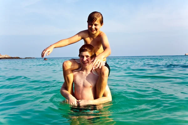 Αδελφοί παίζουν μαζί σε μια όμορφη θάλασσα με κρυστάλλινα cl — Φωτογραφία Αρχείου
