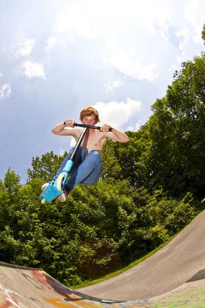 Мальчик летит по воздуху на скутере — стоковое фото