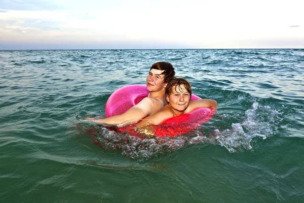 Bröder i en simtur ring har kul i havet — Stockfoto