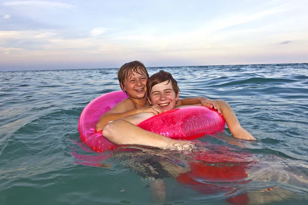 在游泳圈的兄弟们在海洋中玩得开心 — 图库照片