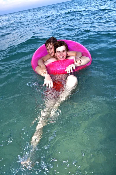 Testvérek egy úszni gyűrű szórakozni az óceánban — Stock Fotó