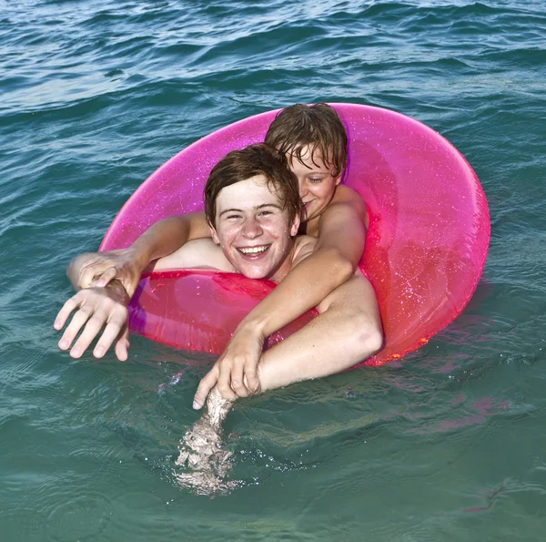 Bavte se bratři do kroužku plavání v oceánu — Stock fotografie