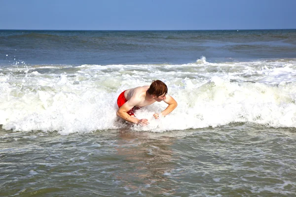 Joven chico es el cuerpo surfeando en las olas —  Fotos de Stock