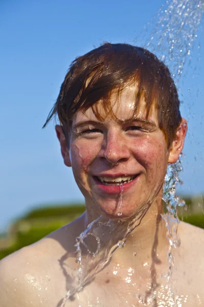 Junge hat eine Dusche am Strand — Stockfoto
