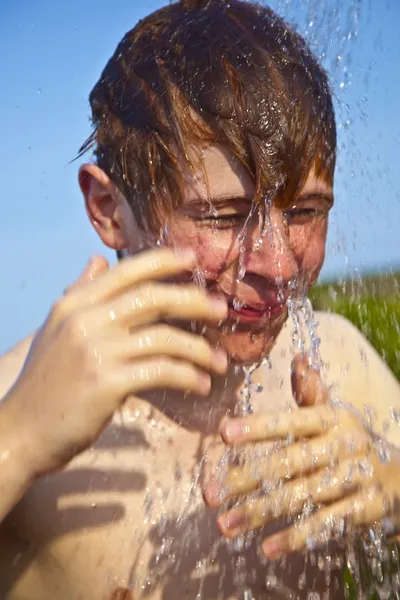 Jongen heeft een douche op het strand — Stockfoto