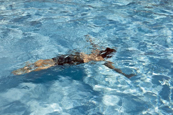 Criança feliz está nadando na piscina — Fotografia de Stock
