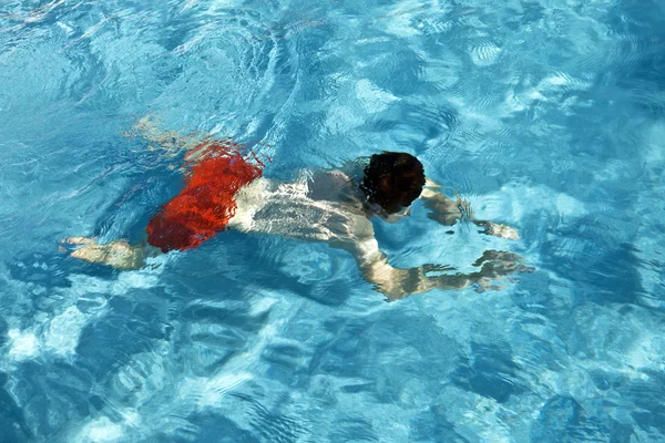 Αγόρι είναι swimminmg στην εξωτερική πισίνα σε μια ηλιόλουστη ημέρα — Φωτογραφία Αρχείου