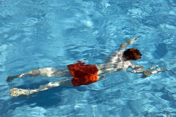 Menino é natação na piscina exterior em um dia ensolarado — Fotografia de Stock