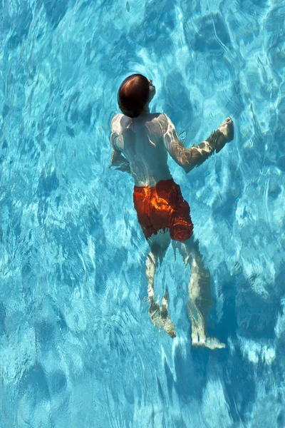Menino é natação na piscina exterior em um dia ensolarado — Fotografia de Stock