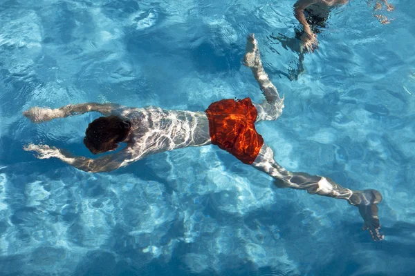 Pojken är swimminmg i utomhuspoolen på en solig dag — Stockfoto