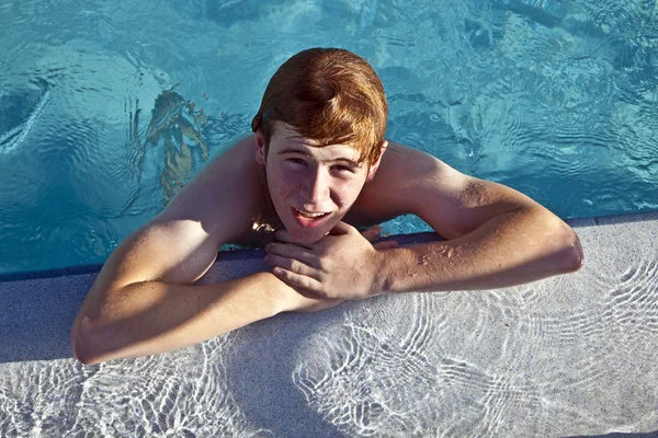 Pojke vilar på sin ellbow vid kanten av poolen — Stockfoto