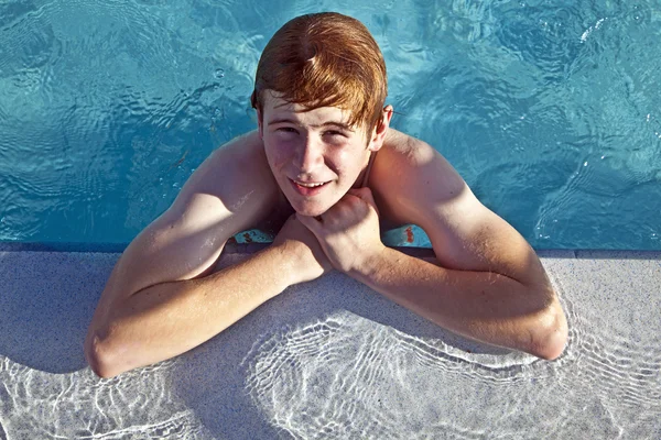 Menino descansa em seu cotovelo na borda da piscina — Fotografia de Stock