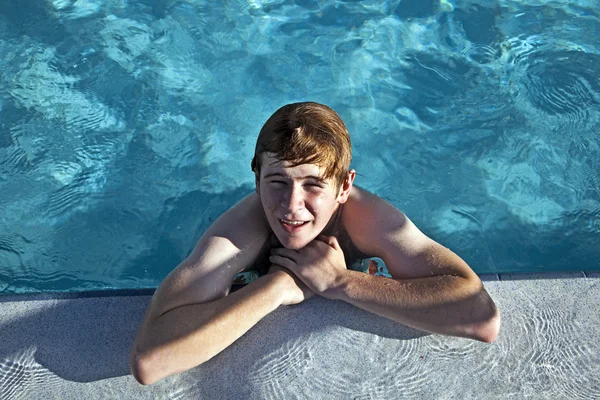 Garçon repose sur son coude au bord de la piscine — Photo