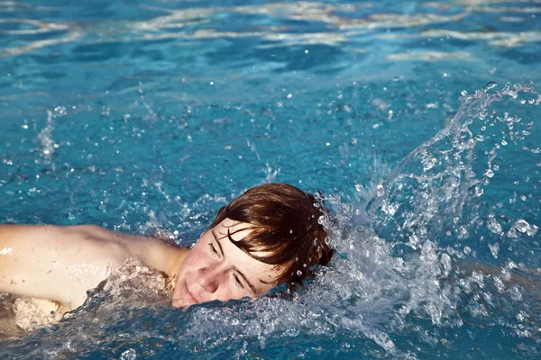Мальчик ползает в бассейне — стоковое фото