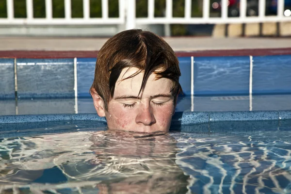 Jongen ontspannen aan de rand van het buitenzwembad — Stockfoto