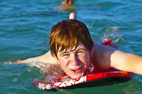 Мальчик ползает по доске для сёрфинга — стоковое фото