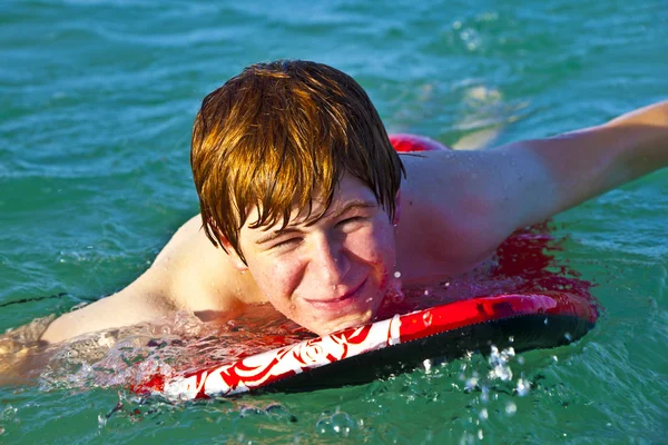 Jonge jongen is kruipen op de surfplank — Stockfoto