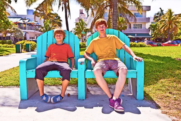 Deux frères sont assis sur un banc de parc art déco dans le sud de Miami — Photo