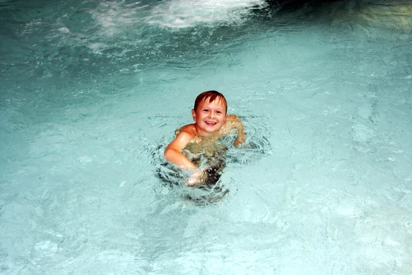 Молодий хлопчик розважається в громадському критому басейні — стокове фото
