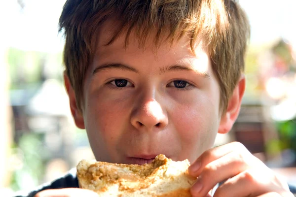 Joven está comiendo tostadas con crema encima, disfrutando de la comida —  Fotos de Stock