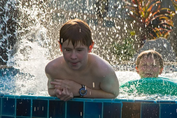 Barn leker i en pool och spottering med vatten — Stockfoto