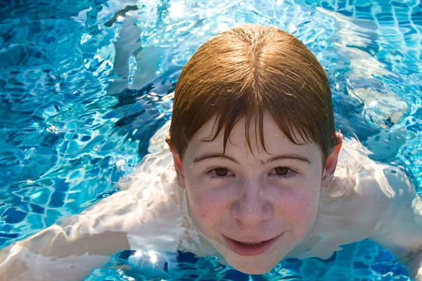 Menino com cabelo vermelho está nadando na piscina e enyoing o fresco — Fotografia de Stock