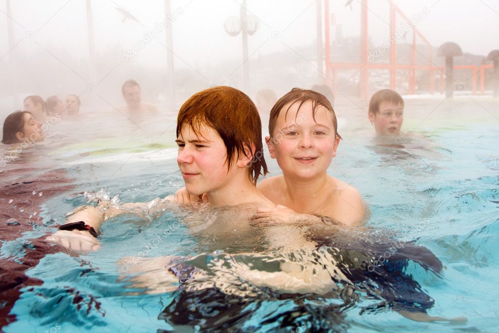 Brothers are swimming in the thermal pool in winter